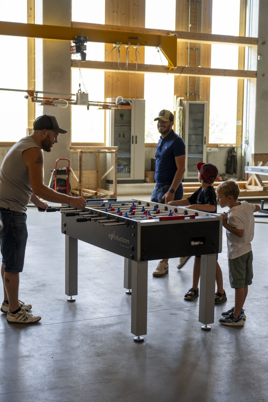 BesucherInnen spielen Tischfußball auf der 100-Jahre-Rubner-Feier in der holzius Heimstatt, umgeben von Vollholz.