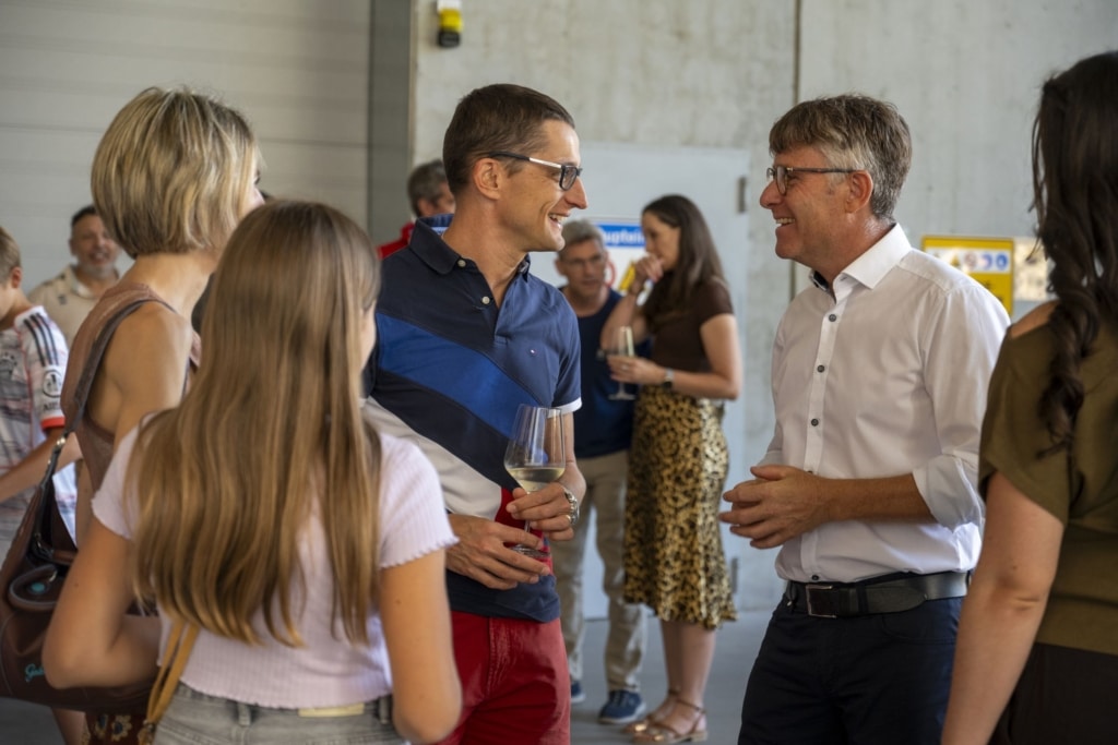 BesucherInnen genießen und unterhalten sich auf der 100-Jahre-Rubner-Feier in der holzius Heimstatt, umgeben von Vollholz.
