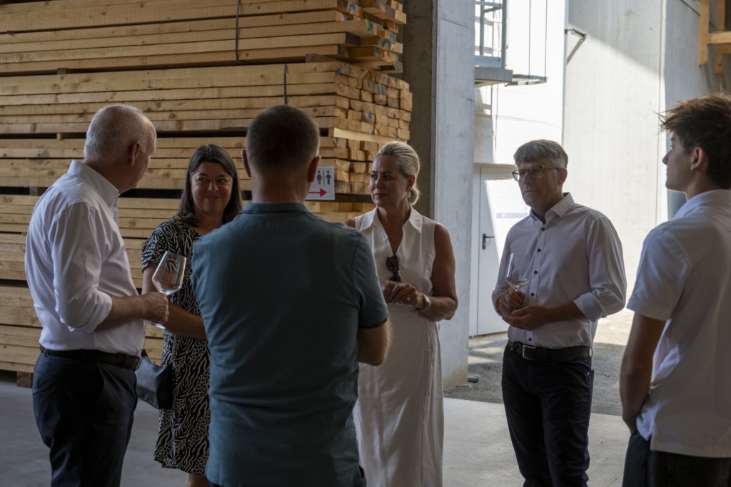 BesucherInnen genießen und unterhalten sich auf der 100-Jahre-Rubner-Feier in der holzius Heimstatt, umgeben von Vollholz.