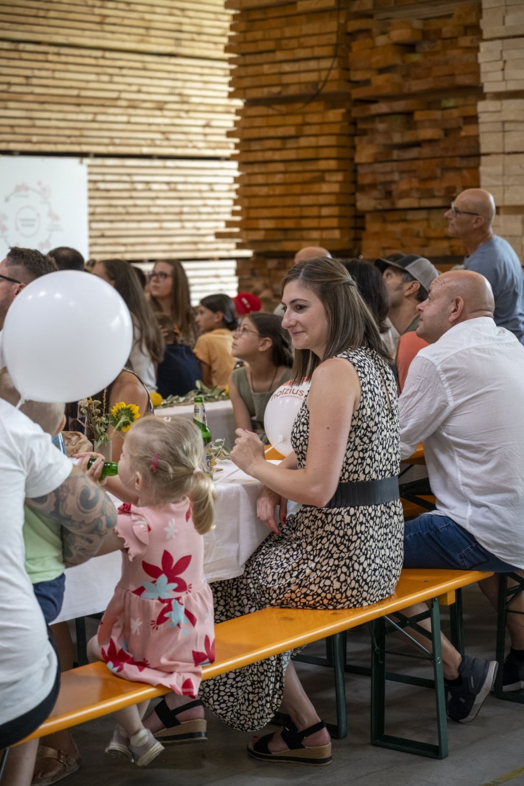 BesucherInnen genießen und unterhalten sich auf der 100-Jahre-Rubner-Feier in der holzius Heimstatt, umgeben von Vollholz.